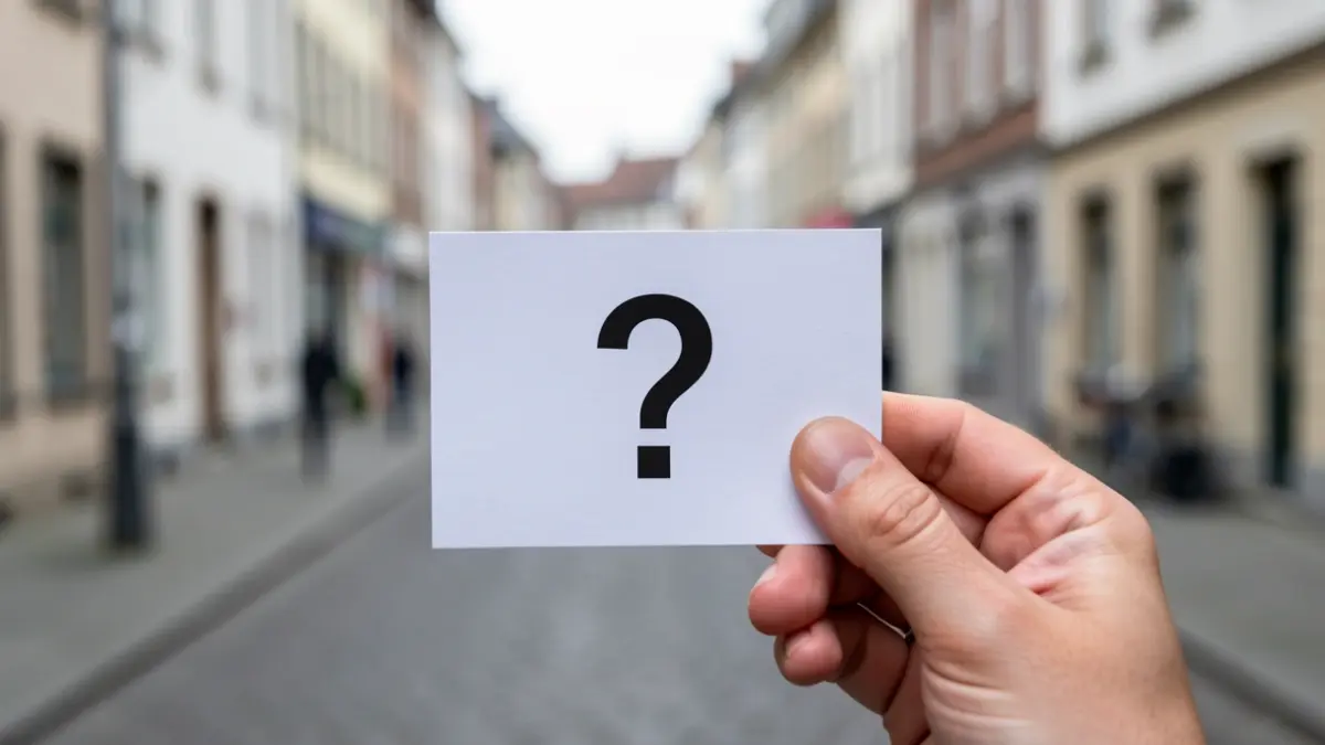 Main tenant une carte de client mystère avec un point d'interrogation, dans une rue de Namur.